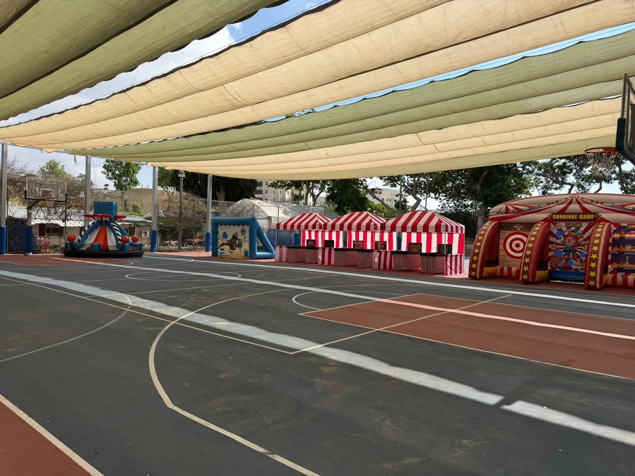 הפנינג והפעלות — דוכני קרנבל ומתקנים מתנפחים במגרש מוצל